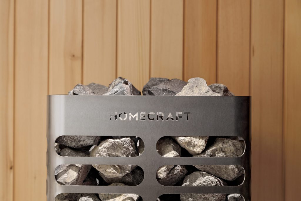 Homecraft Revive sauna heater against cedar, with stones visible through the louvres and branding on the band