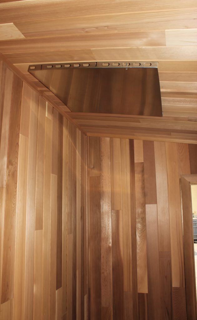 Stainless steel ceiling heat shield above the door of a cedar sauna