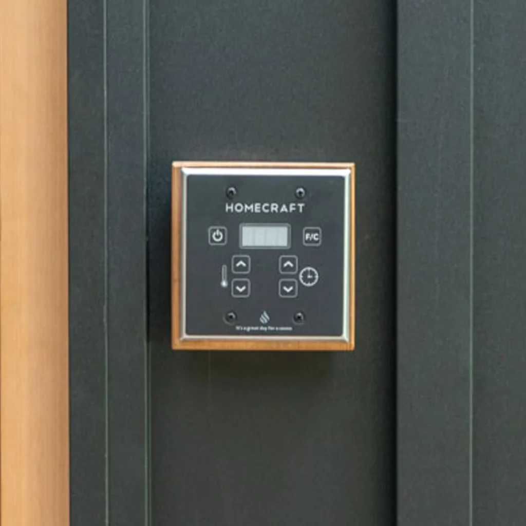Gold-bezel Homecraft sauna control touchpad on a dark green-grey panel beside cedar trim