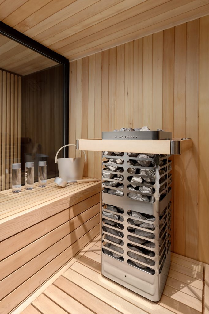 Homecraft Revive sauna heater with stainless guard and pale wood rail beside folded towels