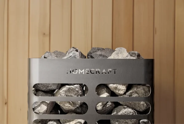 Rough stones packed into a Homecraft sauna heater above its vented steel body, with cedar boards behind